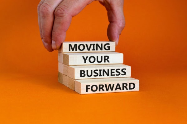 person stacking blocks that say Moving Your Business Forward