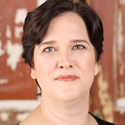 Dez Stephens PCC headshot photo, woman with dark hair in front of red and white background