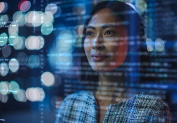 woman looking at transparent screen with code and light spots