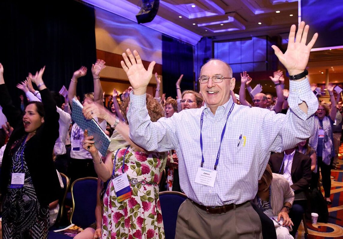 ICF Converge 2017 attendees standing with their hands raised, celebrating joyfully during the conference.