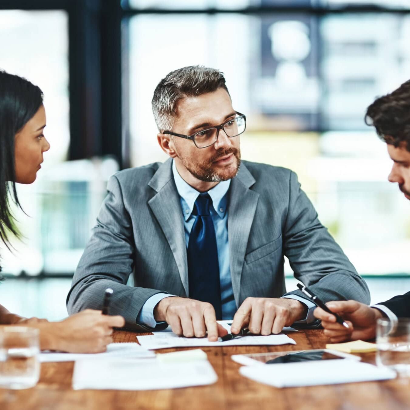 A group of professionals discuss Strategic Alliances in a group setting at a table.