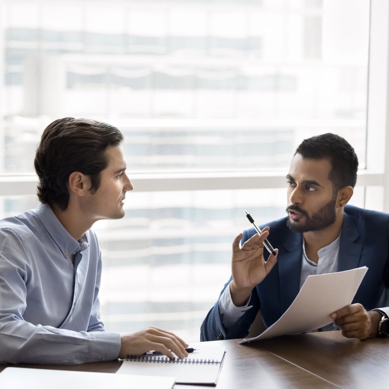 Two men are talking in an office setting on how to advance the coaching profession