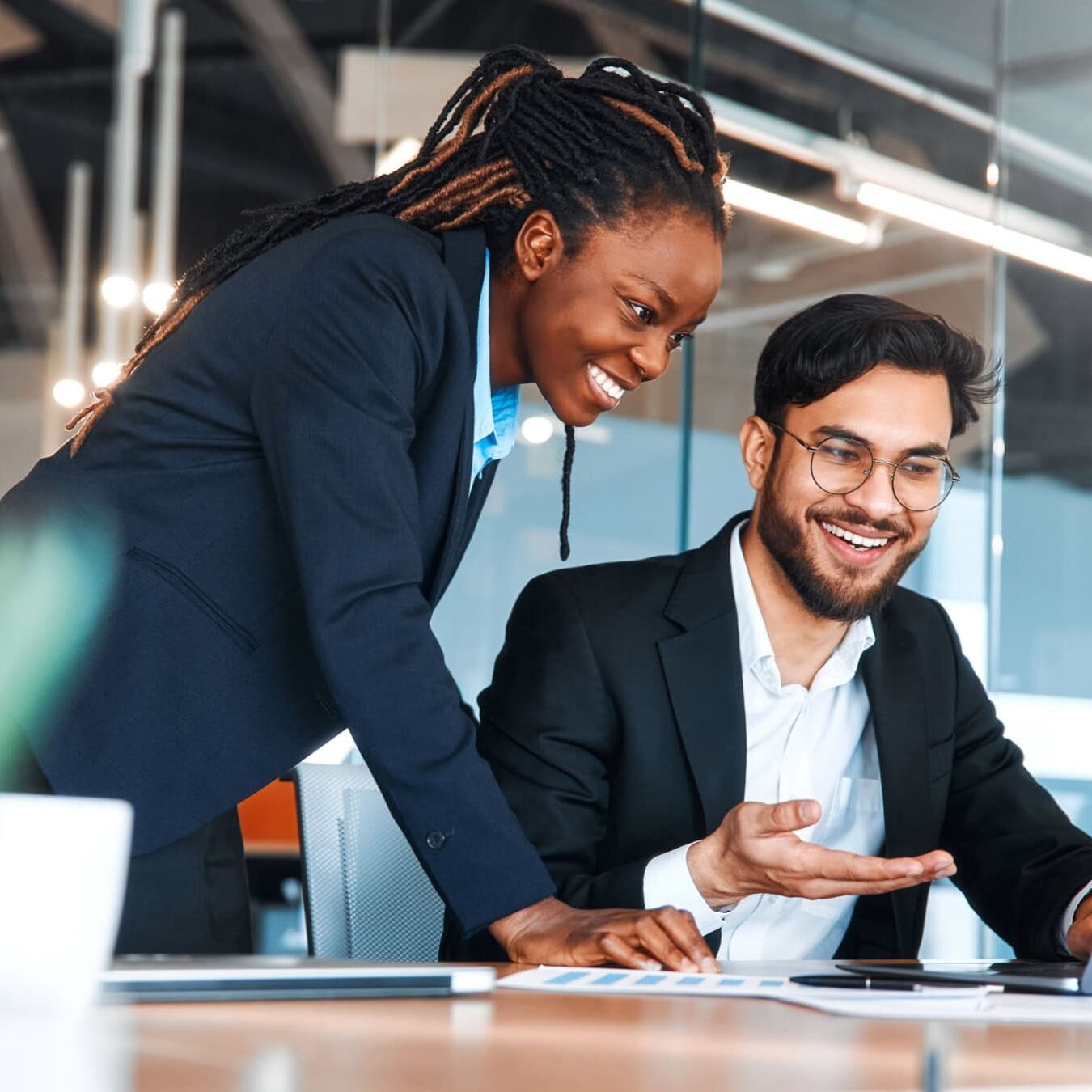 A woman is showing a man using a computer the business partner list, so he can save with his ICF Membership