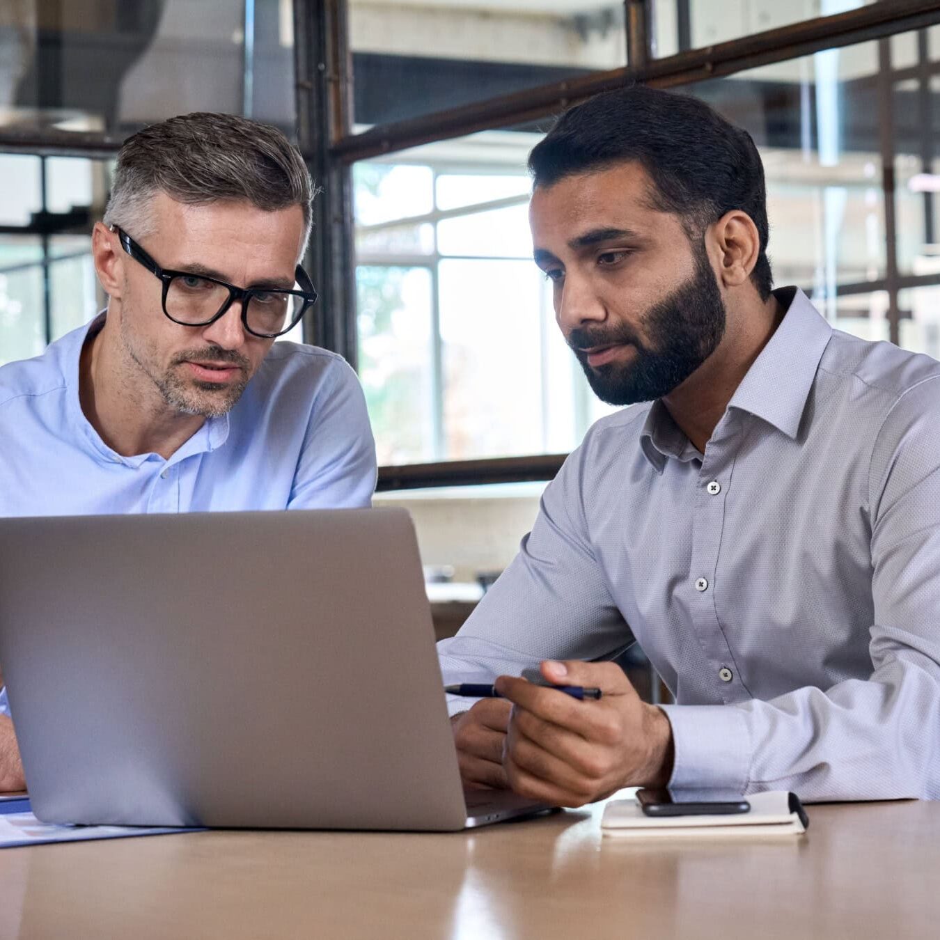 Two men look at a laptop to registration for an exam in a professional office