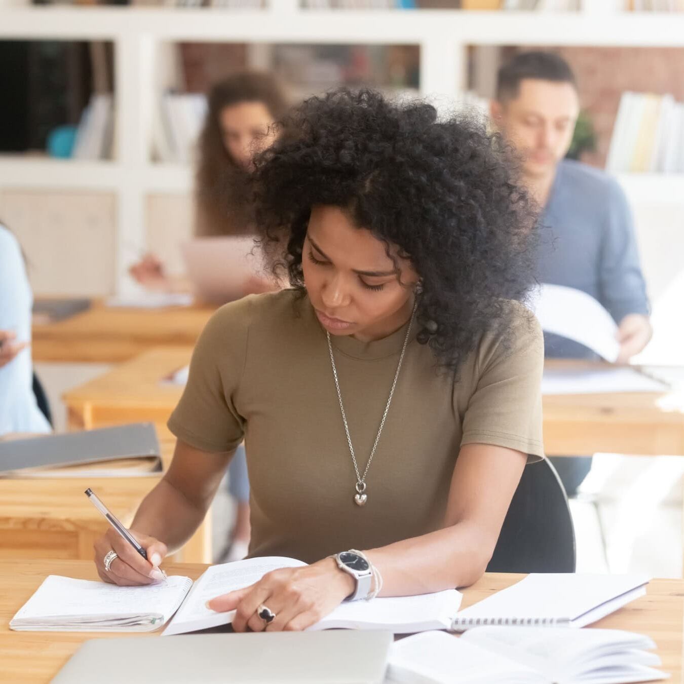 A student is writing notes in her notebook in a classroom