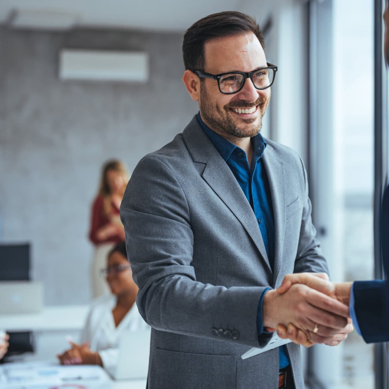 A man shakes hands with another man in an office after discussing the ICF credential educational requirements.
