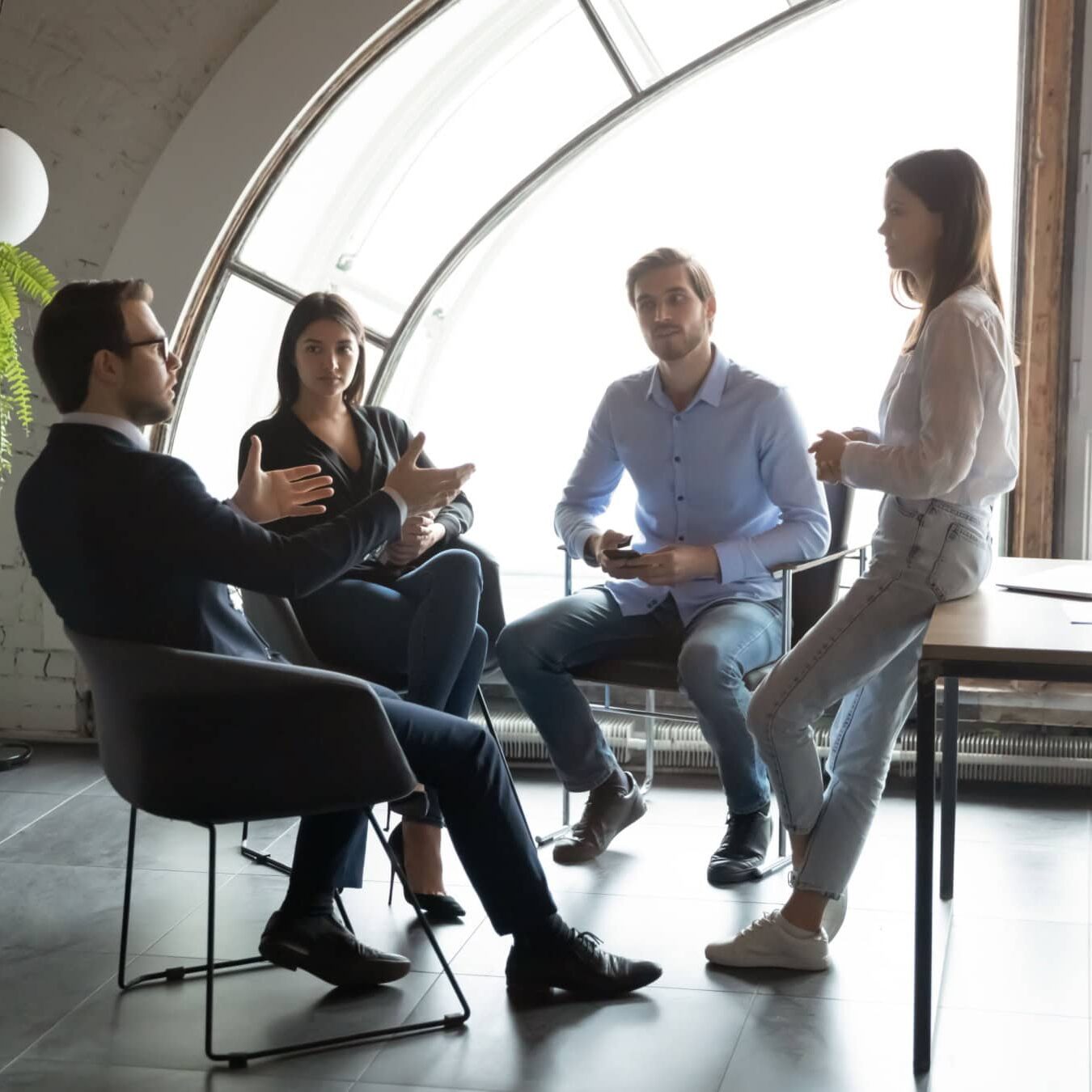 A group of people meet in a casual work environment to discuss coaching ethics.