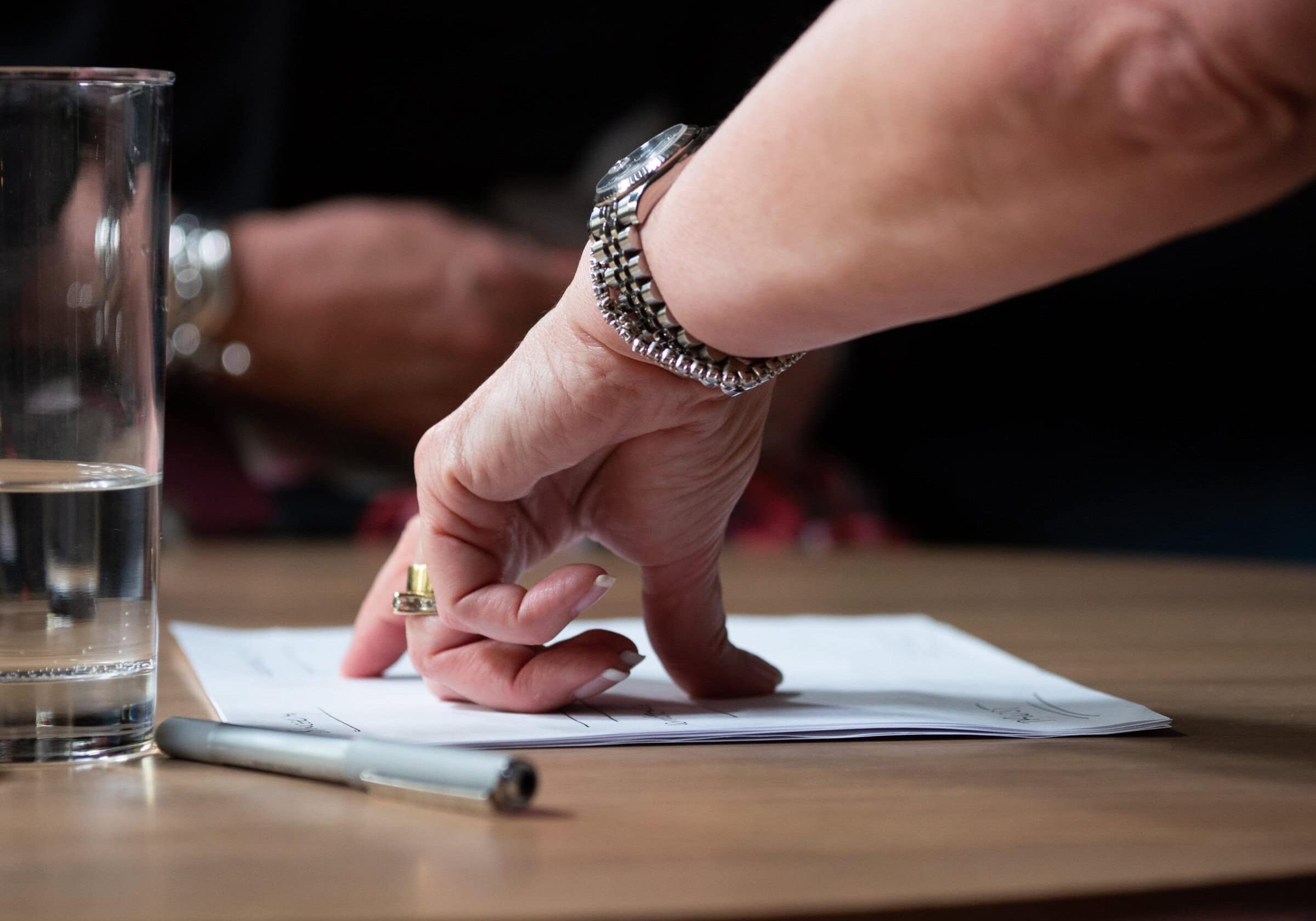 A hand gesturing over a document on a table, emphasizing decision-making and coaching focus.