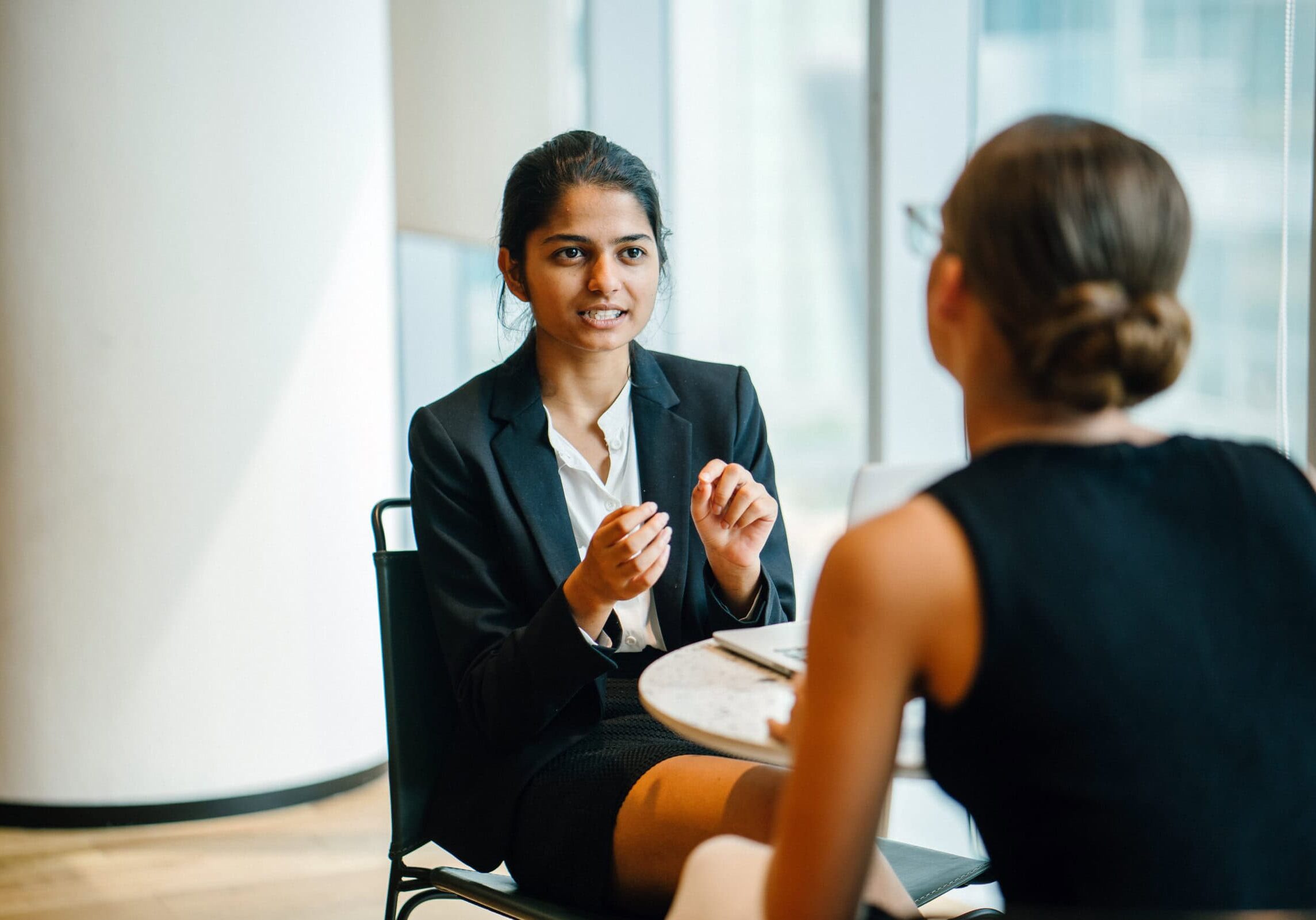 Professional woman in a business suit engaged in a one-on-one coaching session with a colleague, representing ICF-certified coaching.
