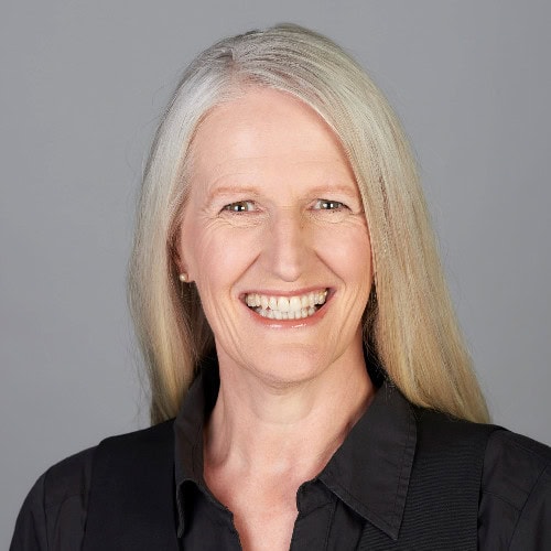 Kristen Dierolf ACTC MCC headshot photo, smiling woman with blond hair wearing black shirt in front of light gray background