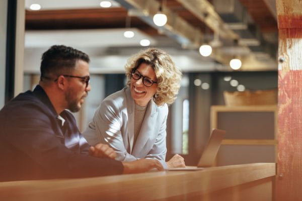 man and woman meeting and looking at a laptop with the woman smiling