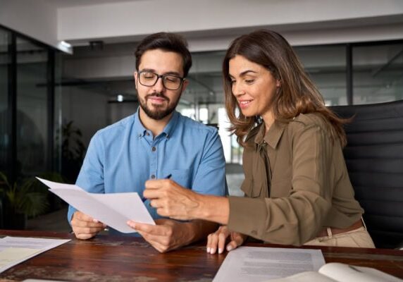 client holding papers while coach points things out on the papers with a pen