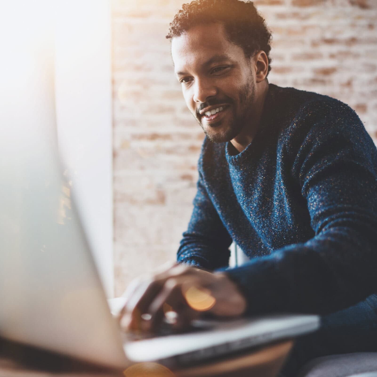 man leaning forward to put his hand on a laptop keyboard