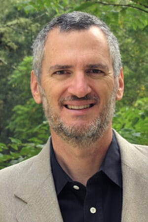 Doug Silsbee headshot photo, smiling man with gray hair wearing light colored blazer and black collared shirt outside