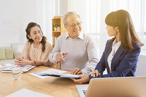 two older people sitting next to a younger coach who is showing them something on some paper and a laptop