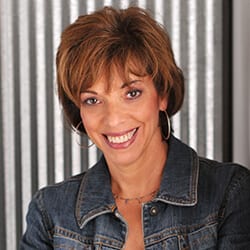 Sue McMahon PCC headshot photo, smiling woman with short brown hair wearing a jean jacket in front of neutral background
