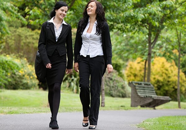two women walking while talking in a park