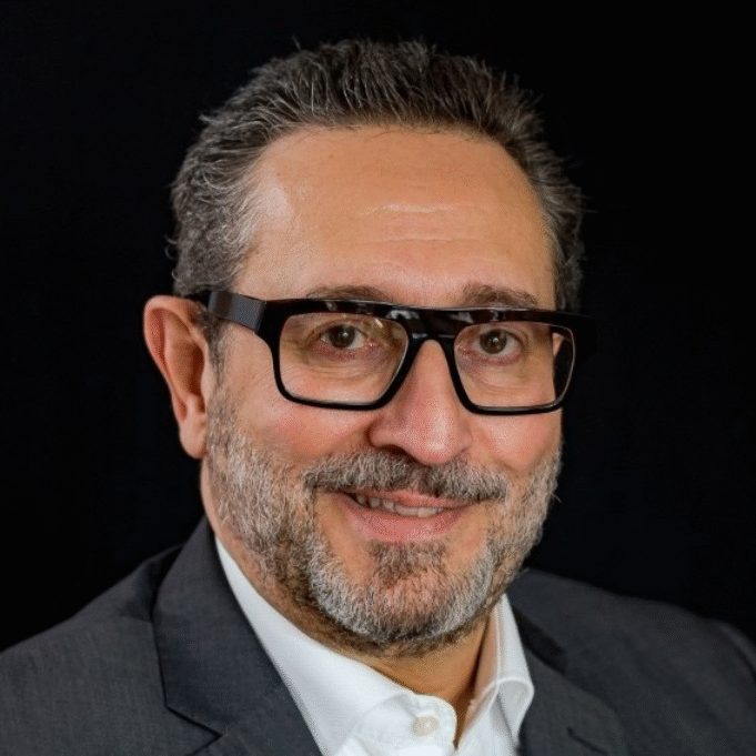 Joano Luiz Pasqual, MCC, headshot, a smiling man is wearing glasses and a button down white shirt with a suit jacket.