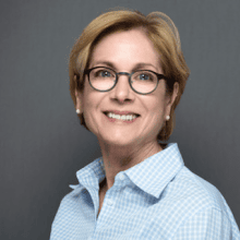 Pandora Ray PCC headshot photo, smiling woman with light short hair wearing a light blue shirt in front of gray background